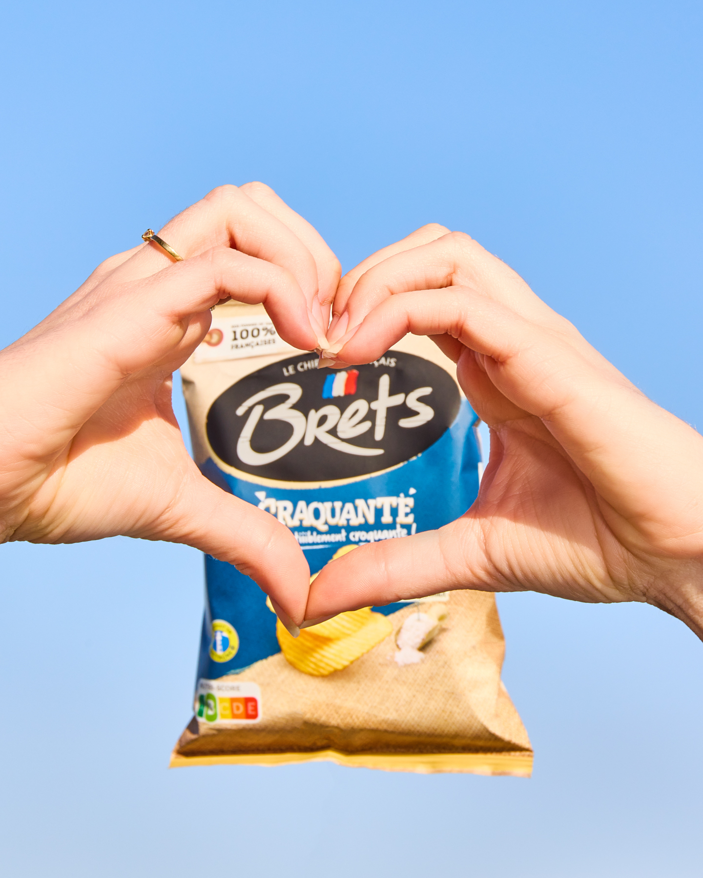 Une paire de mains fait un coeur devant un paquet de chips